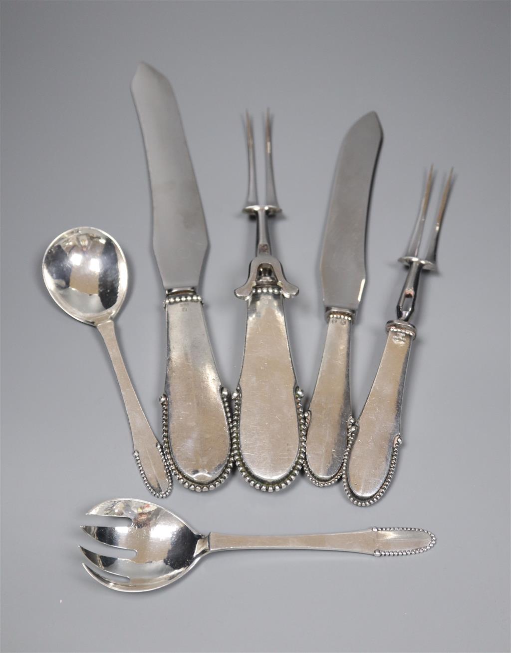 A 1920s Georg Jensen silver handled carving knife and fork, a similar smaller knife and fork and a pair of